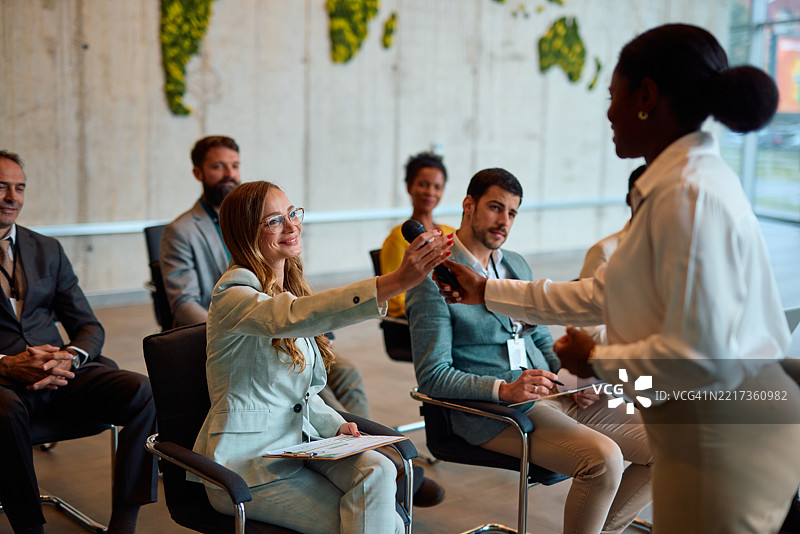 女商人在研讨会上将麦克风递给观众成员图片素材