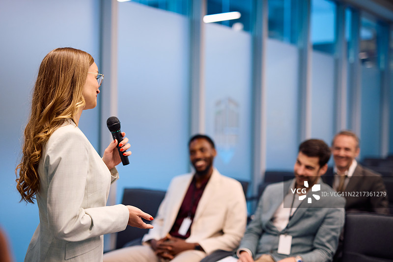 年轻女商人在会议上使用麦克风发言图片素材