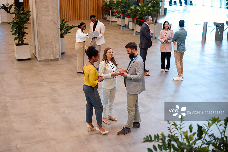 商务人士在会议休息期间进行网络交流并使用数字平板电脑图片素材