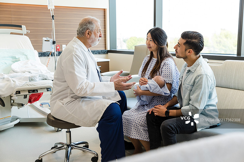 医生在病房里与父母讨论新生儿情况图片素材