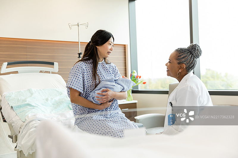 快乐的新妈妈在医院房间里抱着她的新生儿图片素材
