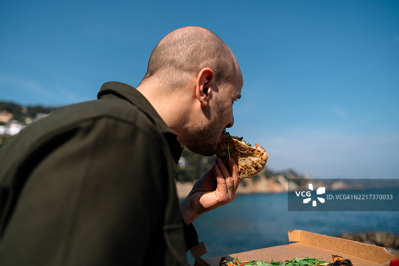 侧面视角的男人在天空下吃东西图片素材