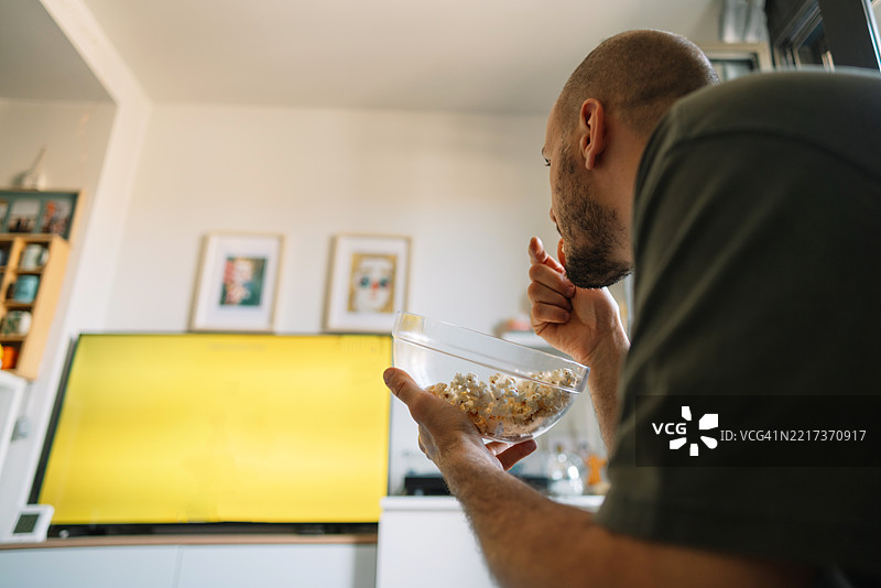 男人在家沙发上看电视，边吃爆米花图片素材