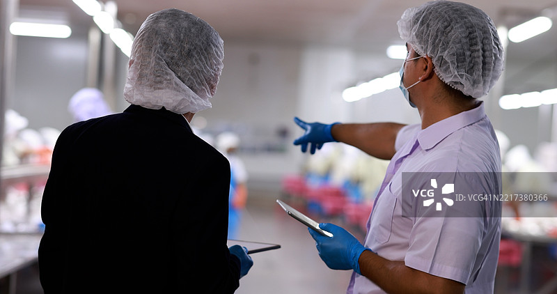 一位商人或投资者正在与罐头鱼厂的首席食品生产经理讨论。图片素材