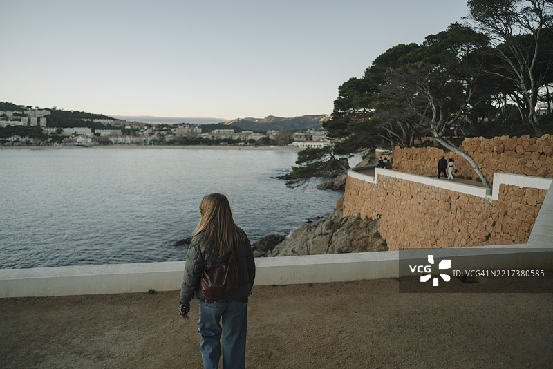 湖边站着的女人背影，背景是晴朗的天空图片素材
