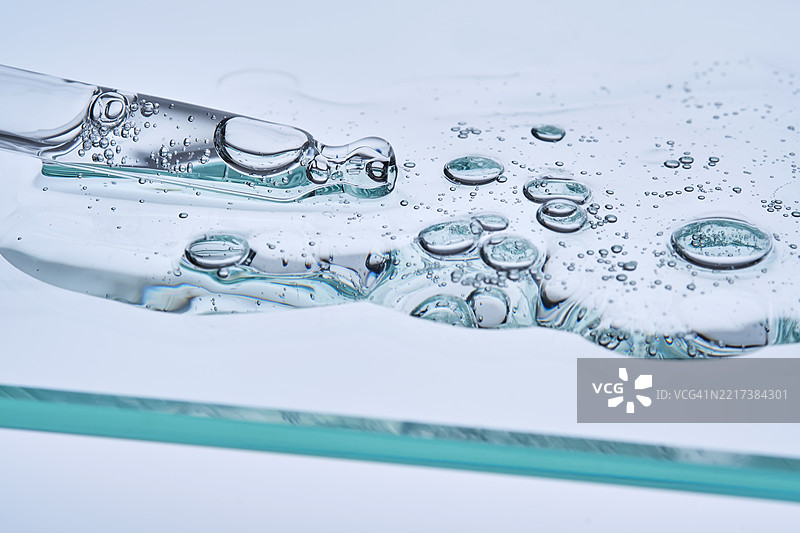 蓝色背景上的含肽精华液与滴管，质地细腻图片素材