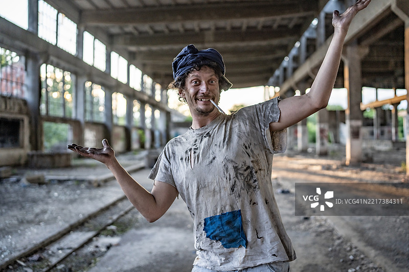 在日落时分，顽皮的工人在废弃的工业仓库中摆姿势图片素材