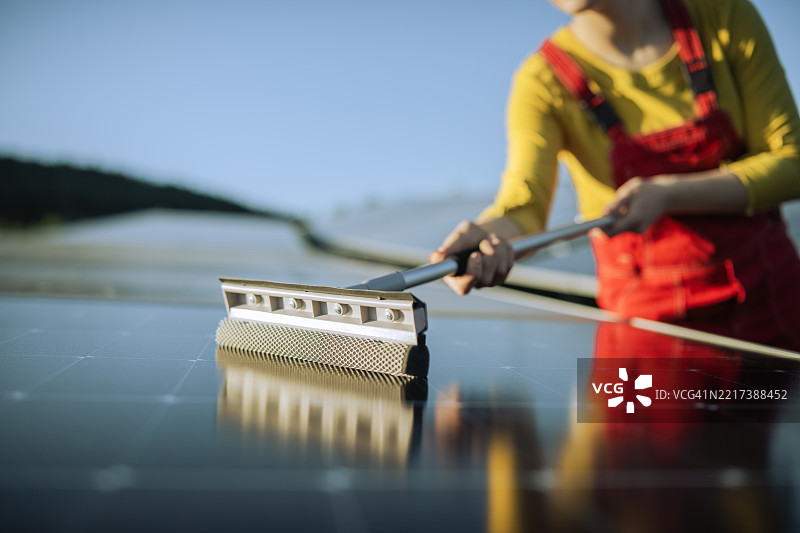 女性在清洁太阳能电池板。图片素材