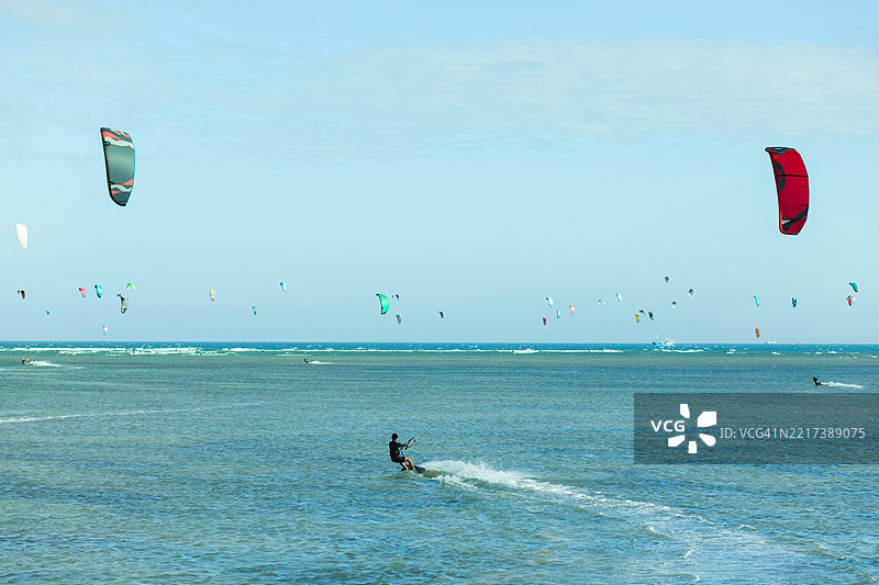 风筝冲浪者在晴朗的蓝天下享受蓝色海洋的水域图片素材