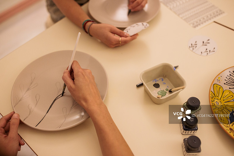 女性在手工艺工作坊学习盘子设计技巧图片素材
