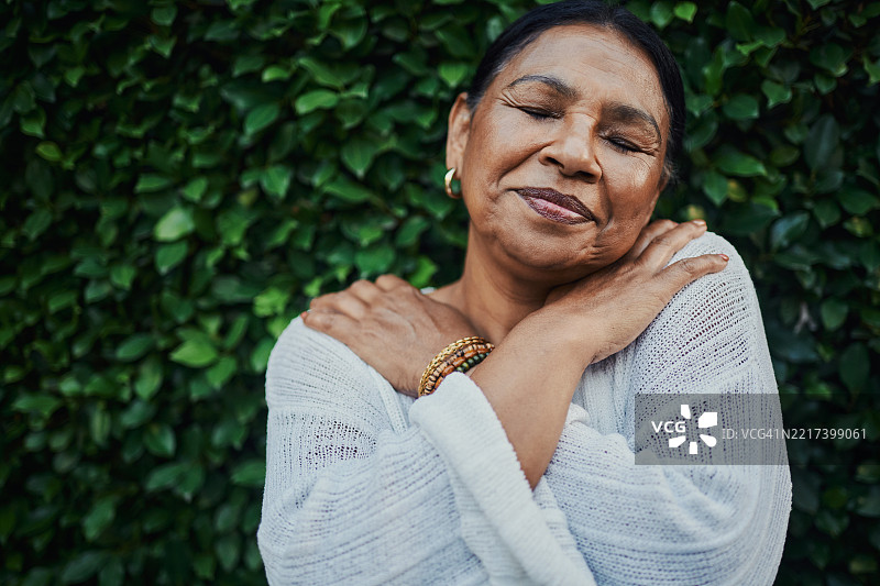 宁静的老年女性在大自然中自我拥抱图片素材