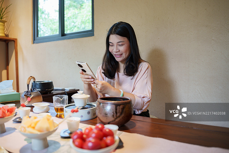 亚洲女性在茶馆使用智能手机图片素材