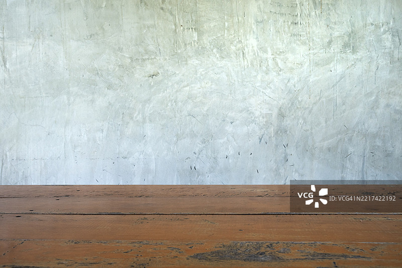 一张全景照片，展示了一张木制长椅位于灰色水泥墙前。图片素材