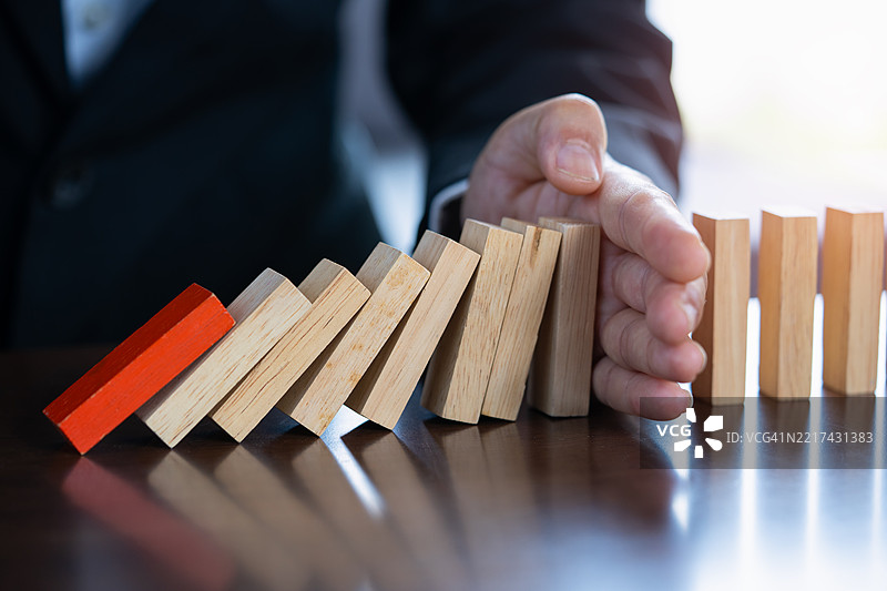 商人用手阻止在商业危机管理概念图中倒下的多米诺骨牌，战略与规划概念，木块，商业风险图片素材