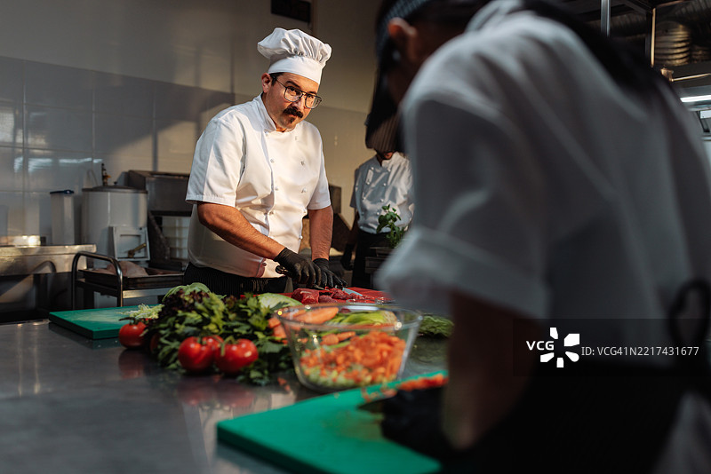 经验丰富的厨师在专业厨房中切肉图片素材