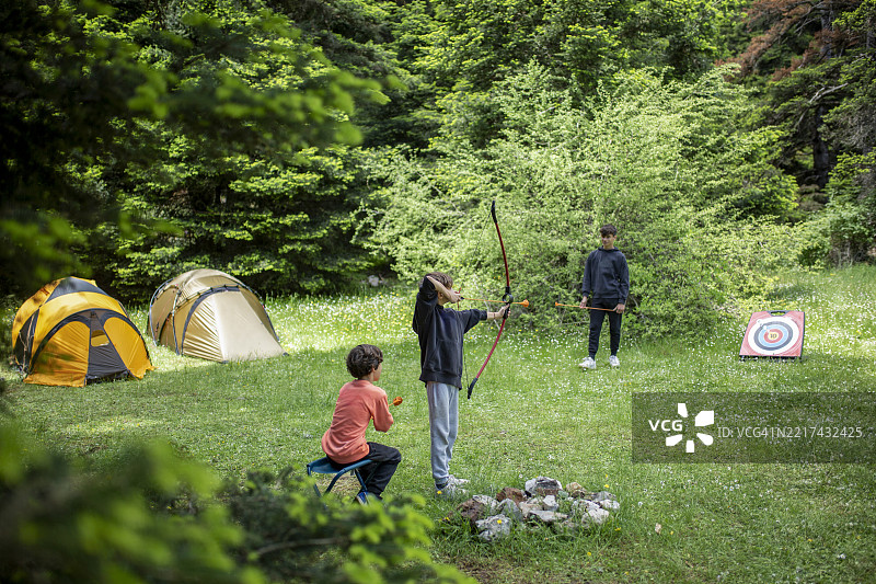 孩子们在夏季露营旅行中在树林里练习射箭图片素材