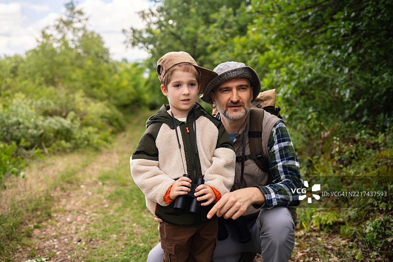 父亲和儿子在户外自然小径上一起观鸟图片素材