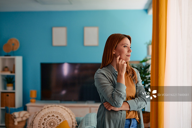 沉思的年轻女性在家中望向窗外图片素材