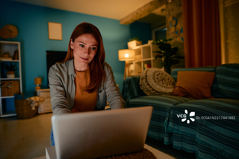 年轻女性在家中夜间使用笔记本电脑工作图片素材