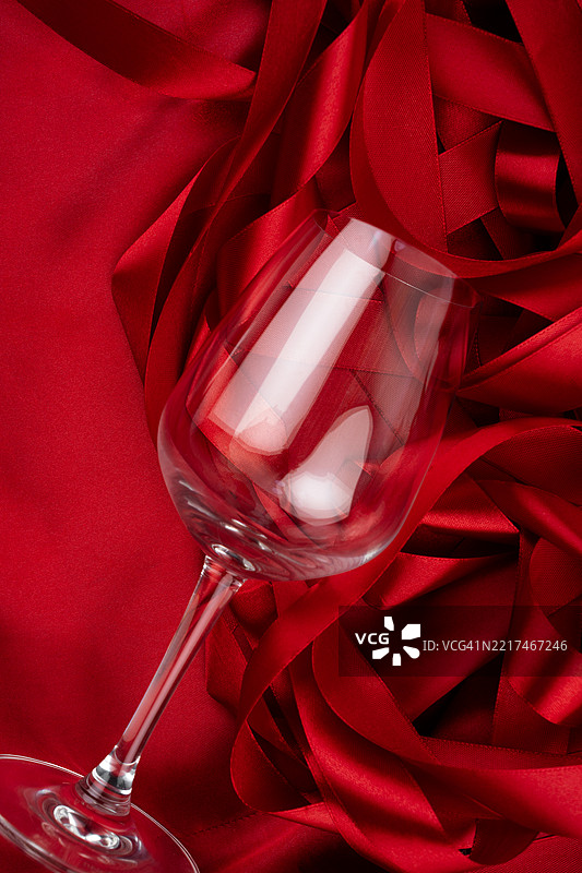 黑色背景上的平铺空酒杯与红色缎带。图片素材
