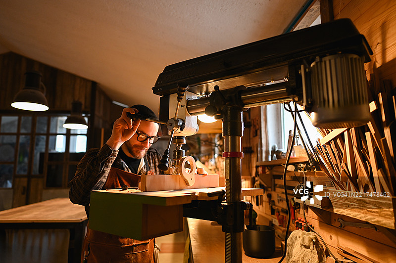 木匠在夜间的工作坊使用钻床图片素材