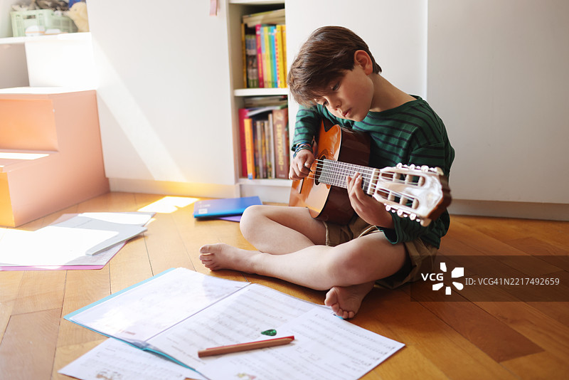 一个小男孩在他的卧室里弹吉他图片素材