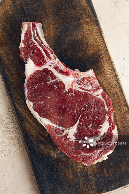 生牛肋眼牛排，牛仔牛排，木质切菜板，大理石桌面，俯视图，无人。图片素材