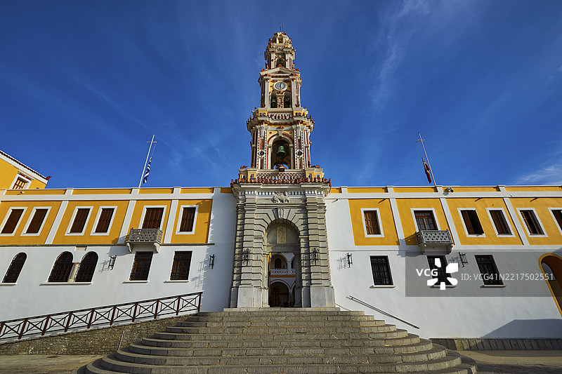 历史建筑与巴洛克风格的教堂塔楼在晴朗的蓝天下，圣周，帕诺尔米提斯湾，帕诺尔米提斯修道院，希米岛，多德卡尼斯群岛，希腊，欧洲图片素材