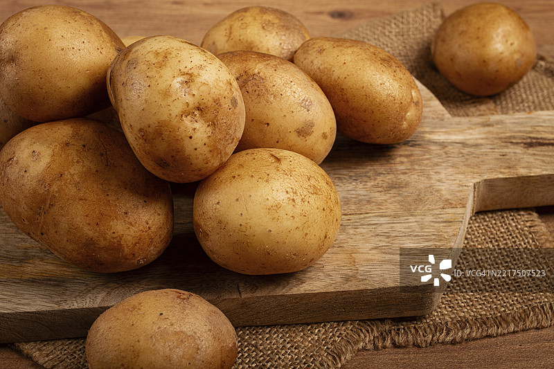 生土豆散落在切菜板上，特写，无人。图片素材