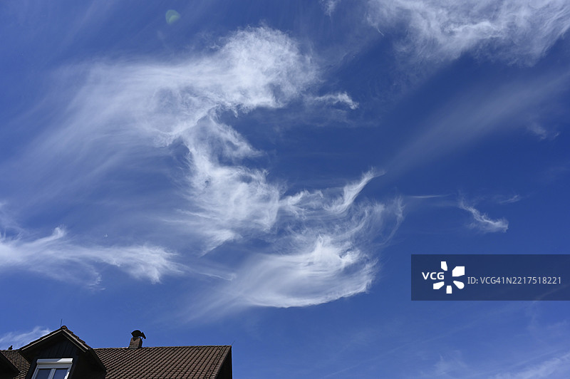 蓝天上住宅楼屋顶上方的羽毛云（卷云），德国下巴伐利亚州普拉特林，欧洲图片素材