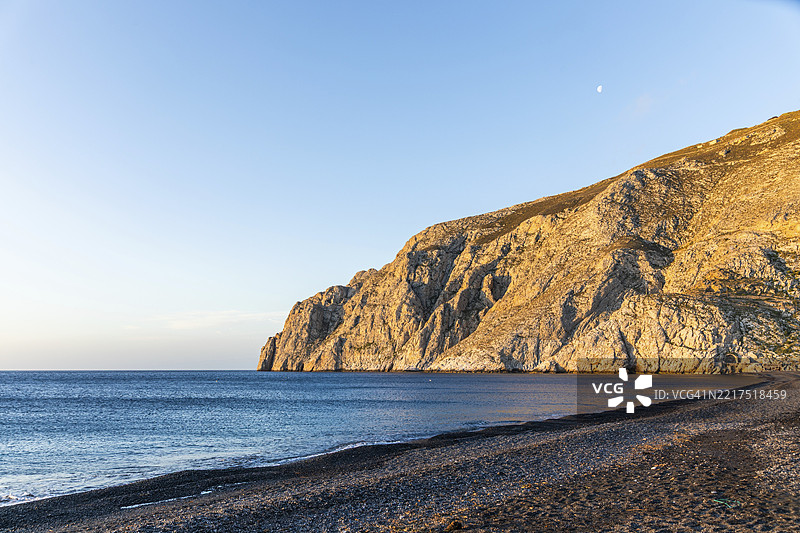 早晨的氛围，月亮悬挂在岩石岬角梅萨·沃诺，熔岩沙滩卡马里海滩，圣托里尼，基克拉泽斯，希腊，欧洲图片素材