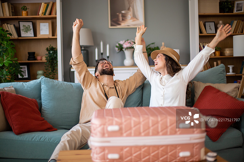 快乐的情侣在家庆祝成功的度假预订图片素材