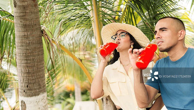 情侣在热带度假时享用清爽饮品图片素材
