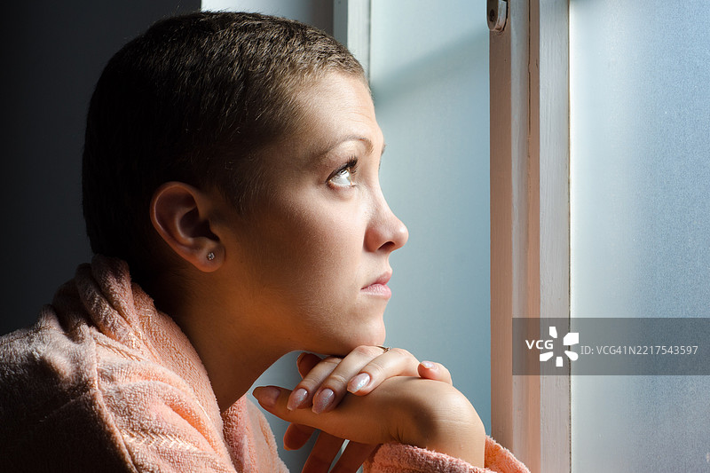 年轻女性癌症患者站在医院窗前图片素材