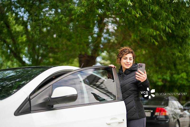 休闲女性站在车辆旁边用手机发信息图片素材