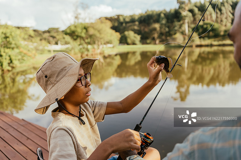 父亲和儿子在湖边钓鱼，放松身心，享受大自然。图片素材