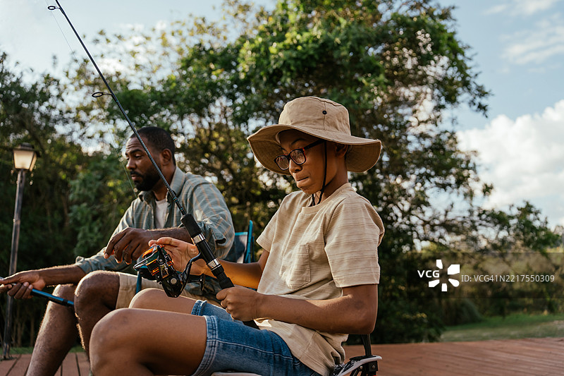 父亲和儿子在湖边钓鱼，放松身心，享受大自然。图片素材