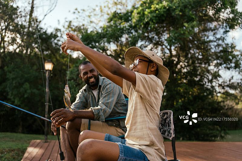 父亲和儿子在湖边钓鱼，放松身心，享受大自然。图片素材