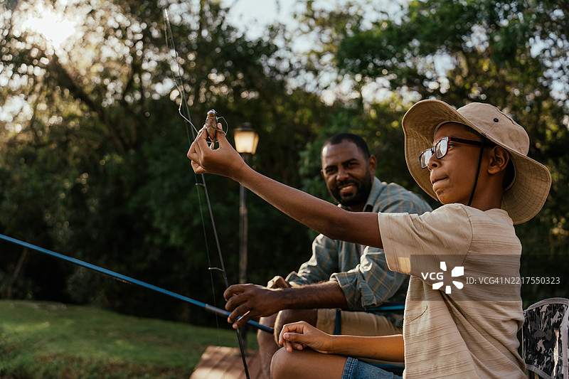 父亲和儿子在湖边钓鱼，放松身心，享受大自然。图片素材