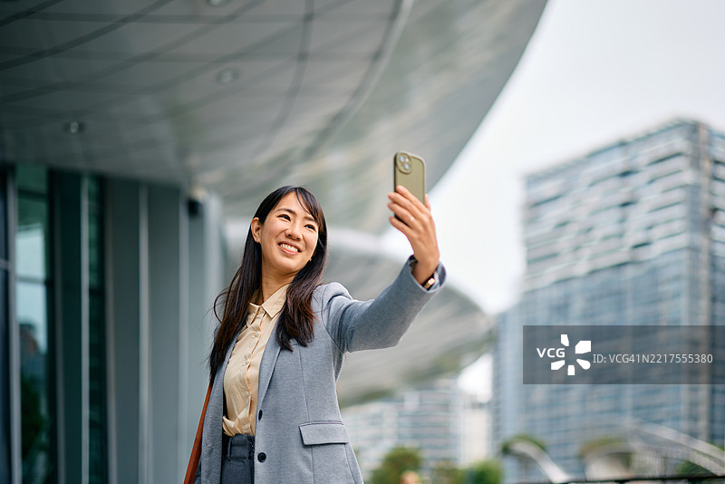 年轻的亚洲女商人在现代城市中自拍图片素材