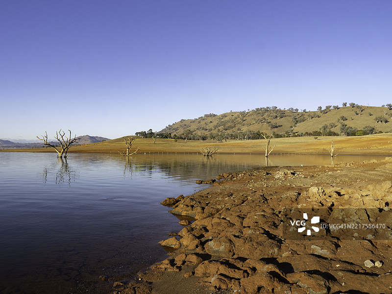 晨光照耀在岩石红土上，映衬着湖面的倒影图片素材