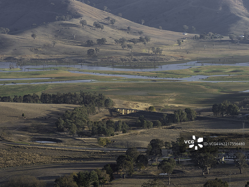 小桥和枯树在蜿蜒的河流中图片素材