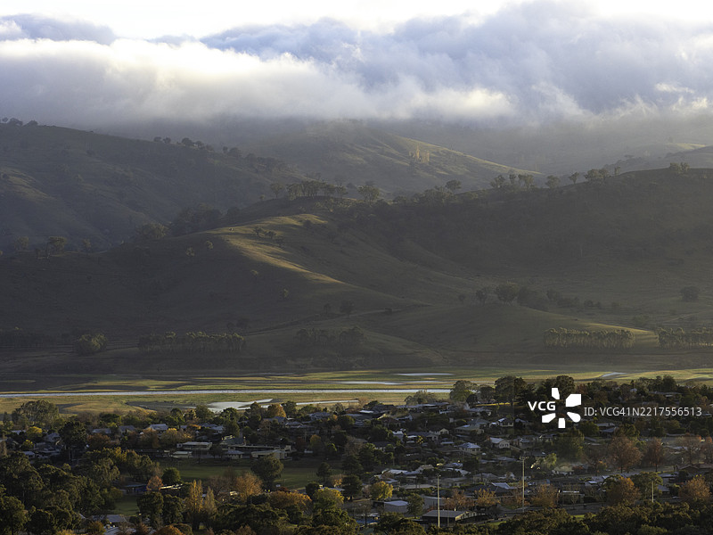 阴郁的山谷房屋与蜿蜒的河流相伴，旁边是起伏的山丘图片素材