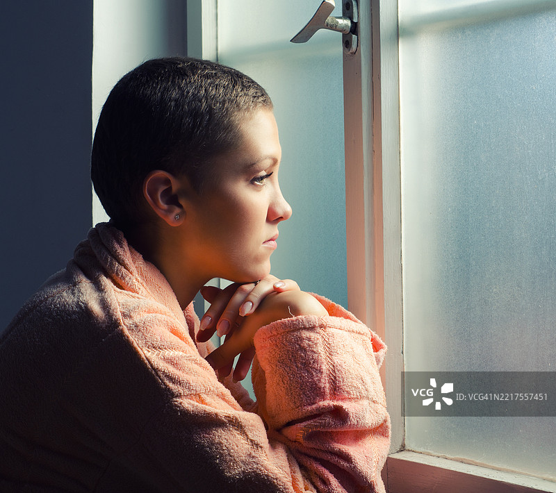 年轻女性癌症患者站在医院窗前图片素材