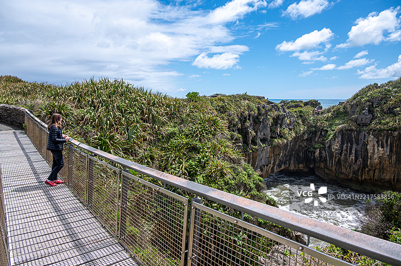 女孩在新西兰帕帕罗阿国家公园欣赏普纳凯基煎饼岩。图片素材