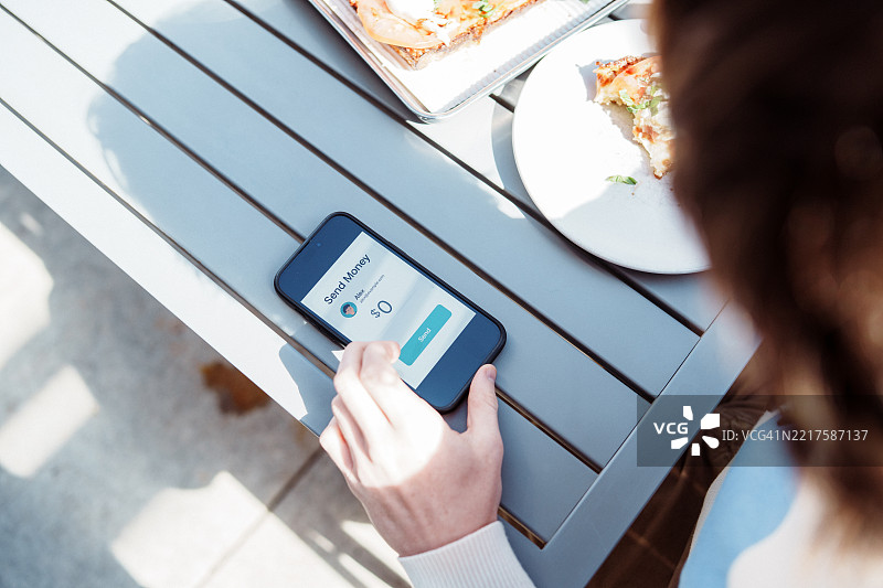 少年在餐厅用手机银行应用向朋友还钱，同时享用美食。图片素材