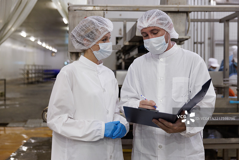食品生产经理在卫生加工设施中讨论工作流程图片素材