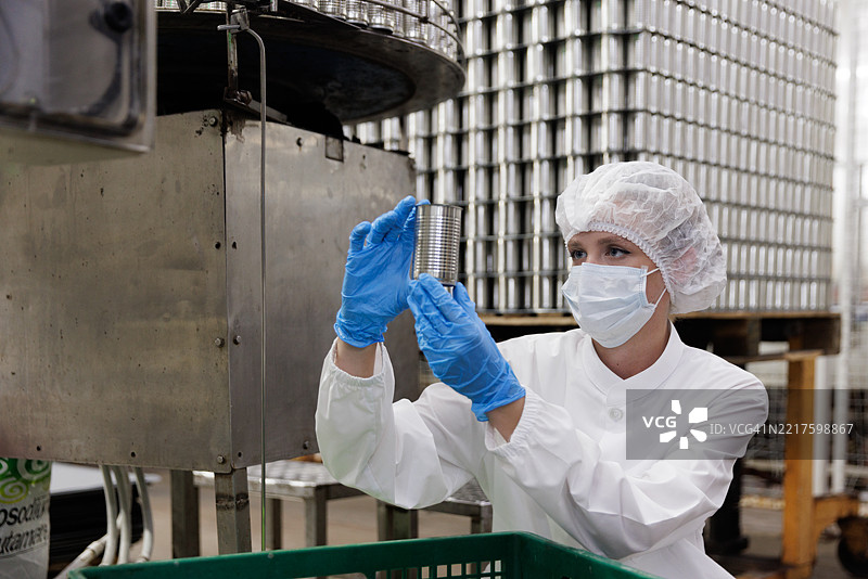 工厂工人在食品生产设施中检查金属罐的质量图片素材