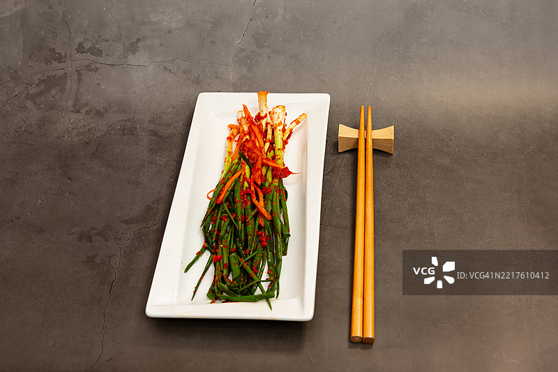 灰色背景下碗中盛着绿葱泡菜和木筷子的俯视图图片素材