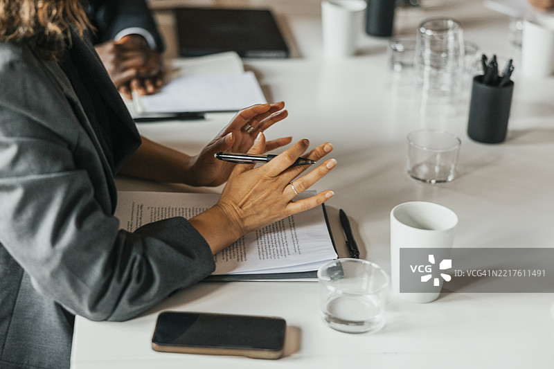 商务女性在办公室团队会议中讨论协议文件的中段镜头图片素材